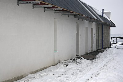 Pohled na vchodovou stranu pasivního domu ve Slaném. Na střeše, připomínající na obou koncích ležící „L“, jsou patrné dvě kolektorové plochy