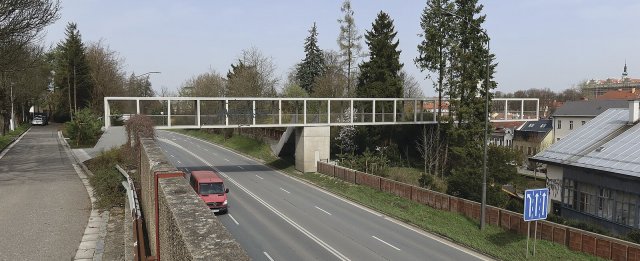 Smetanova lávka z pohledového betonu a oceli nahradila starší už nevyhovující nadchod přes silnici I/35 z roku 1981.